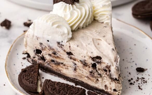a plate with apiece of no bake oreo cheesecake and oreos beside.