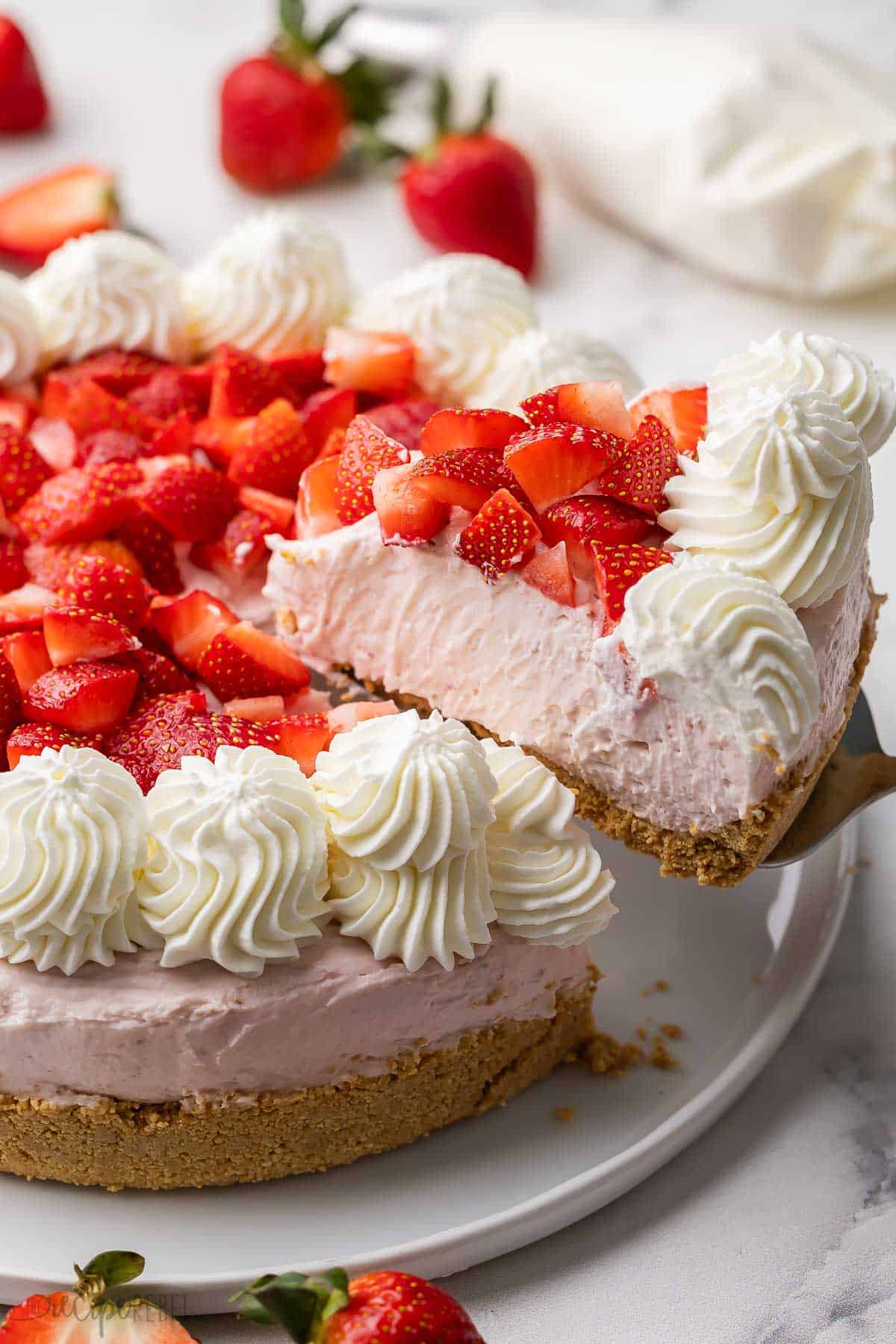 a piece of no bake strawberry cheesecake being lifted off of plate.