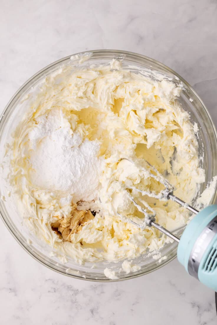 powdered sugar added to bowl of mixed ingredients with mixer beside.