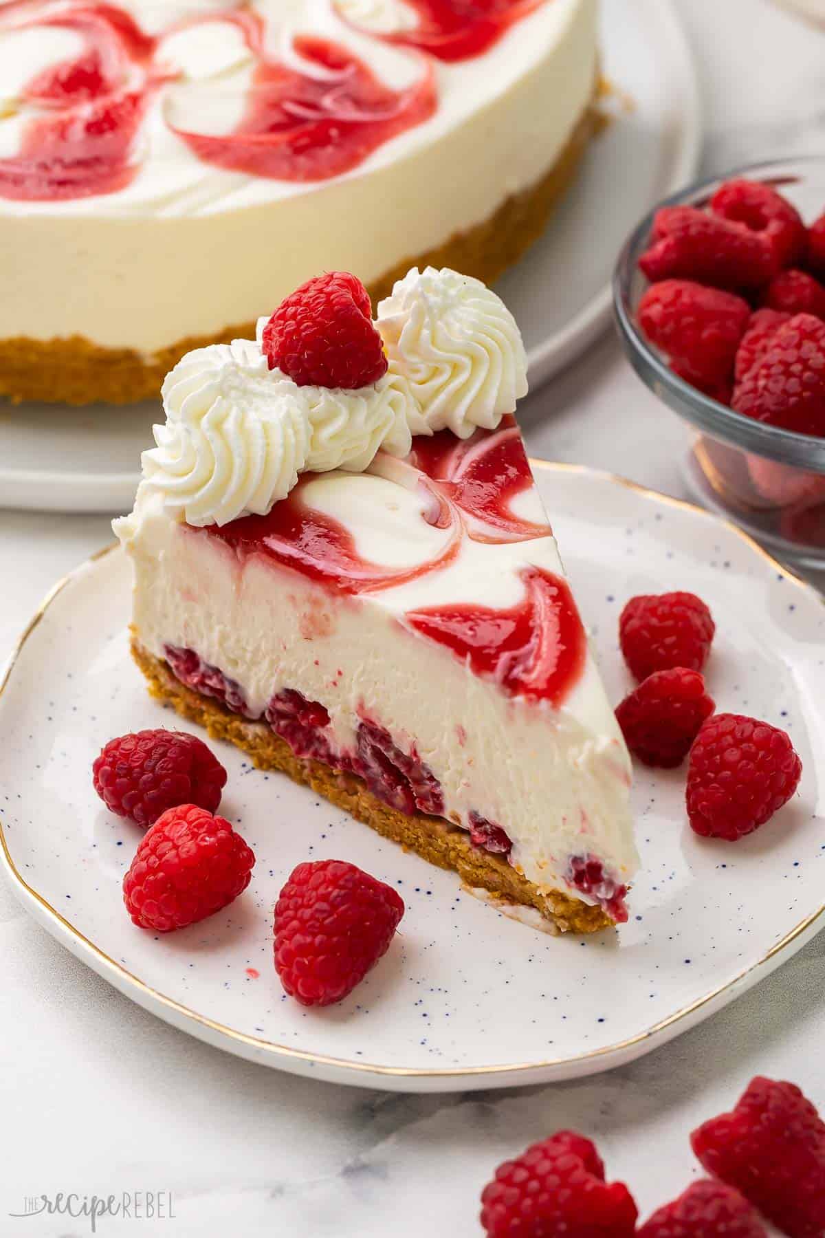 a plate with a piece of cheesecake and raspberries scattered around it.