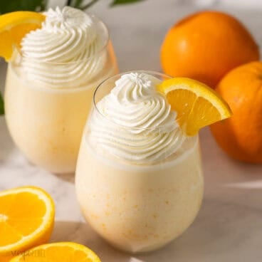 glass of orange creamsicle slushy with orange slice on the side.