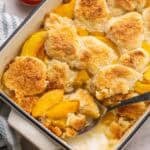 a large spoon scooping peach cobbler.