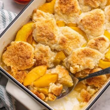 a large spoon scooping peach cobbler.