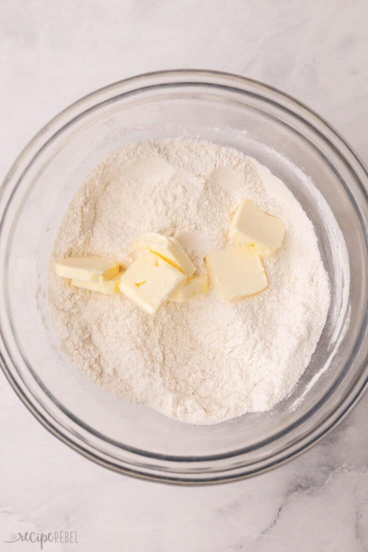 flour in a mixing bowl with cubes of butter added.