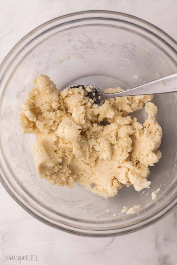 glass mixing bowl with dough and a spoon.