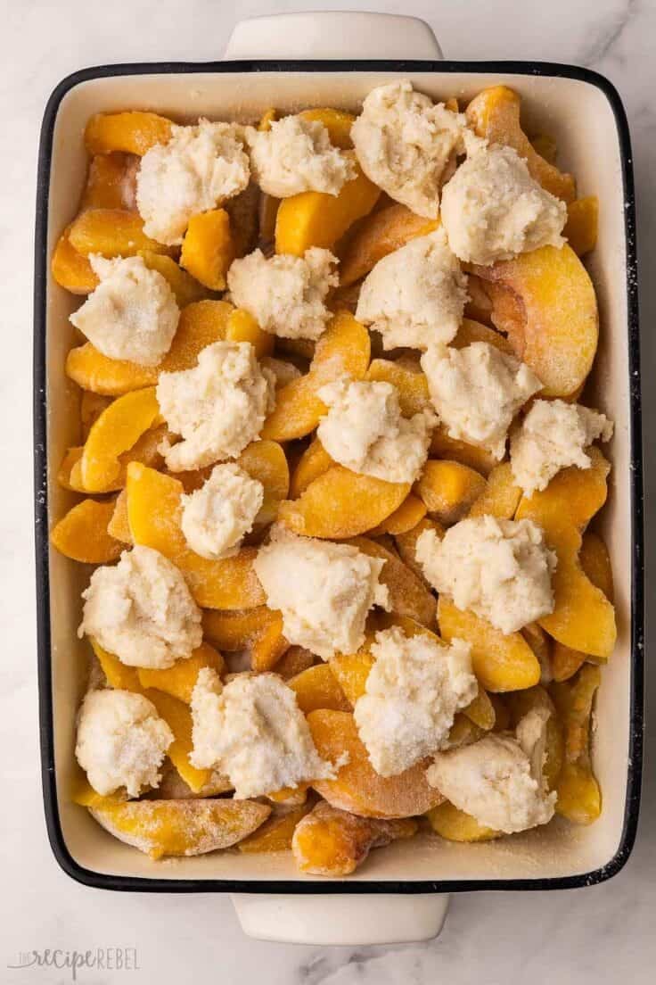 unbaked peach cobbler in a white dish.