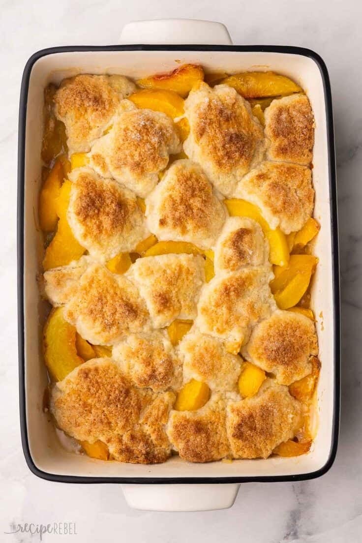 baked peach cobbler in a white baking dish.