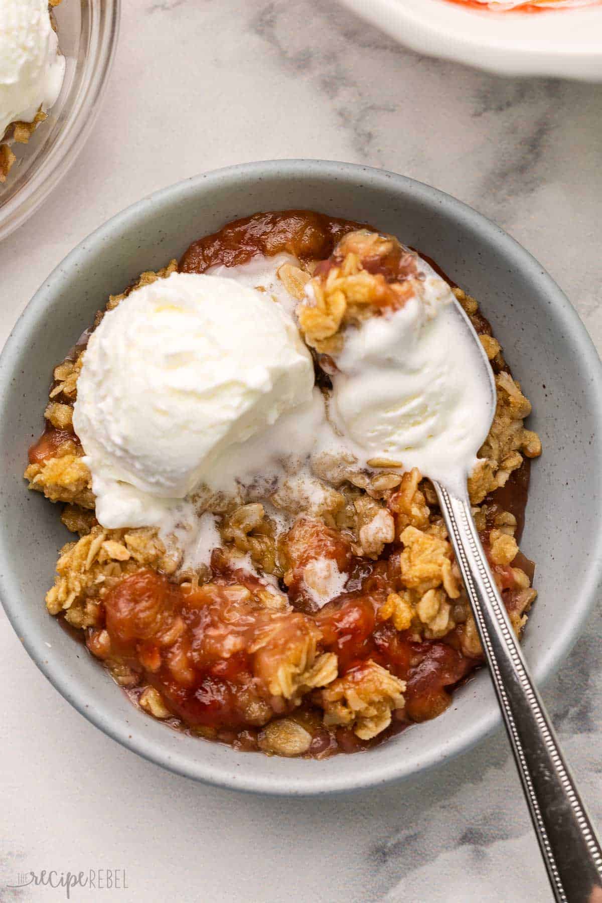 This Rhubarb Crisp recipe is packed with a tangy rhubarb filling and topped with a crunchy oatmeal streusel! Add a big scoop of vanilla ice cream on top for a sweet and tart dessert that's ready in 45 minutes. #rhubarb #dessert #recipe | dessert recipes | rhubarb recipes | rhubarb dessert | fruit crisp | baking recipe | easy recipes a bowl of rhubarb crisp with vanilla ice cream.