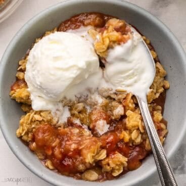 rhubarb crisp in a bowl topped with a scoop of vanilla ice cream.