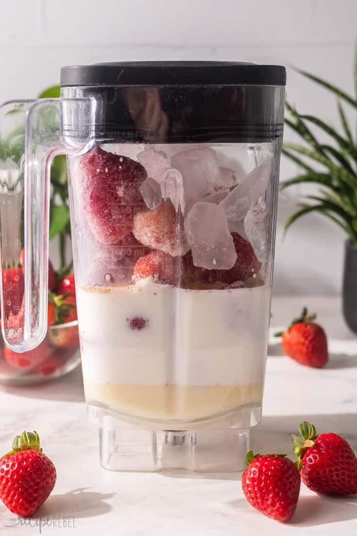 blender full of ingredients for strawberry frappuccino.