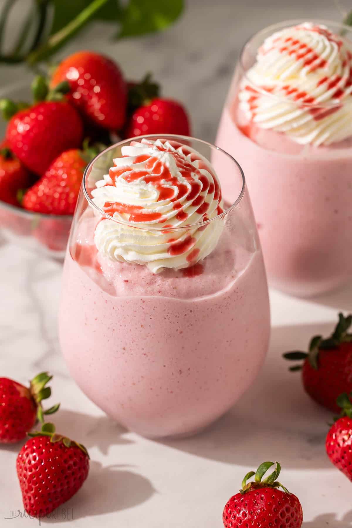 a glass of strawberry frappuccino topped whipped cream.