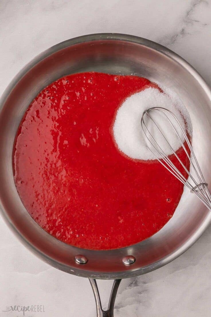 unmixed sugar and strawberry puree in pan with whisk.