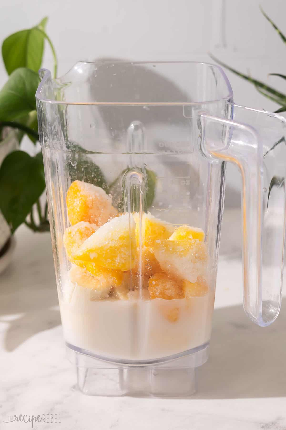 blender full of unmixed tropical smoothie ingredients.