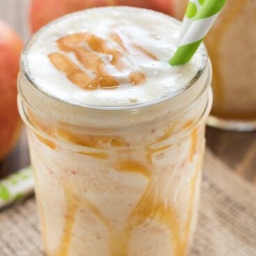 caramel apple smoothie in a mason jar with 2 paper straws.