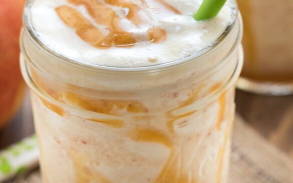caramel apple smoothie in a mason jar with 2 paper straws.