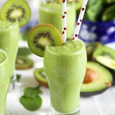 kiwi spinach smoothie in a glass with two straws.