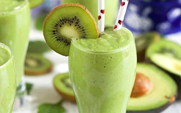 kiwi spinach smoothie in a glass with two straws.