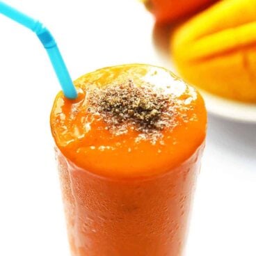 carrot smoothie in a glass with a straw.