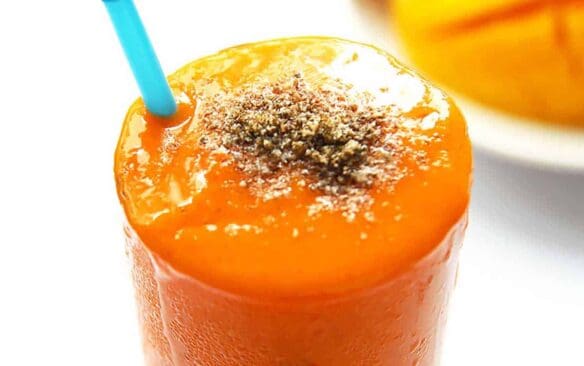 carrot smoothie in a glass with a straw.