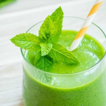 mint green smoothie in a glass garnished with mint.