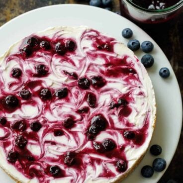no bake blueberry cheesecake on a white plate topped with fresh blueberries.