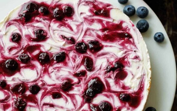 no bake blueberry cheesecake on a white plate topped with fresh blueberries.