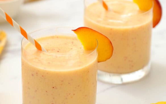 peach honey yogurt smoothie in two glasses with a straw.