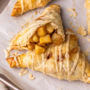 glazed apple turnovers on parchment lined pan.
