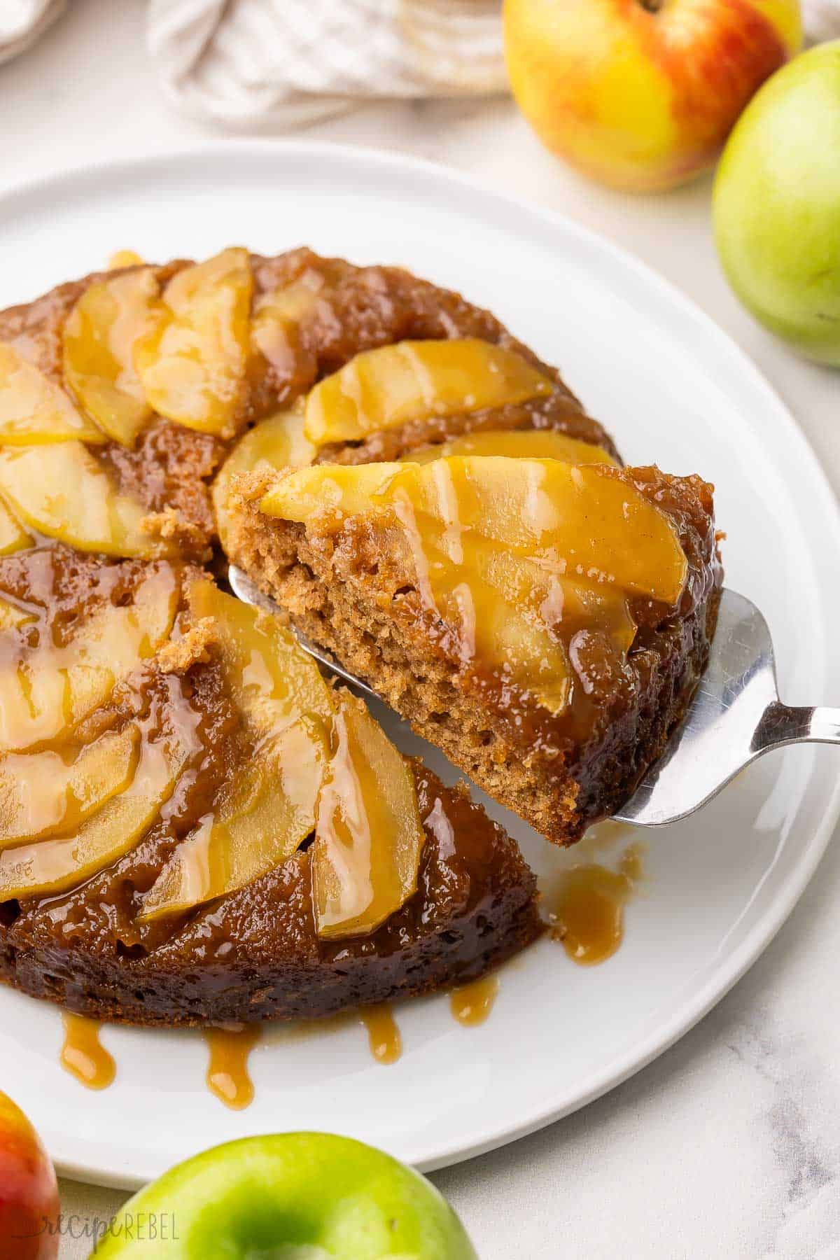 a piece of apple upside down cake being lifted off of plate.