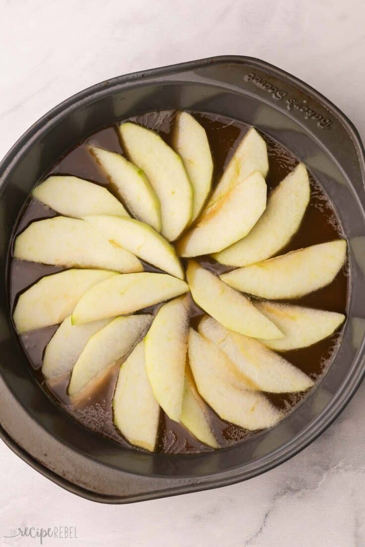 sliced apples and sauce on the bottom of cake pan.