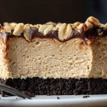 no bake buckeye cheesecake bar with bite taken out of it on a white plate.