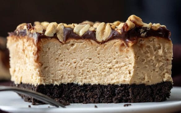 no bake buckeye cheesecake bar with bite taken out of it on a white plate.