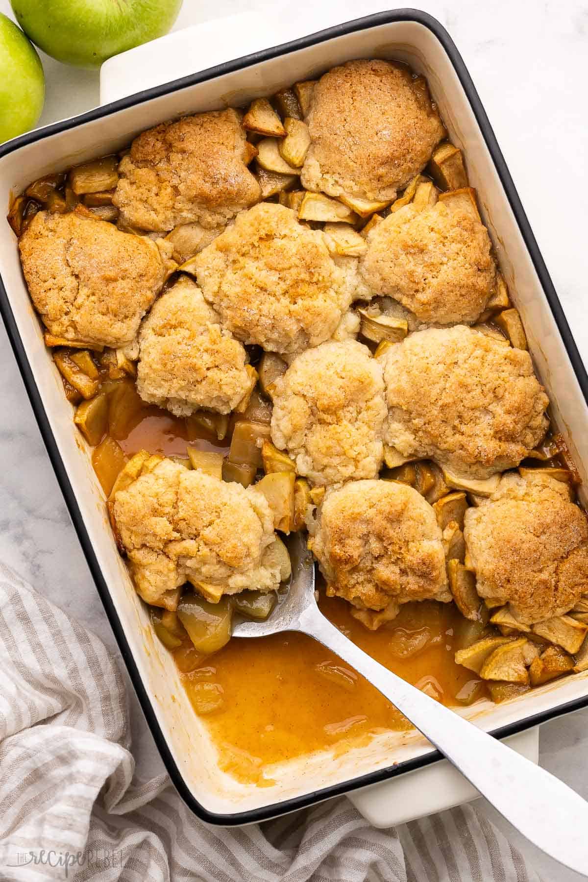 pan of caramel apple cobbler with large spoon in it.