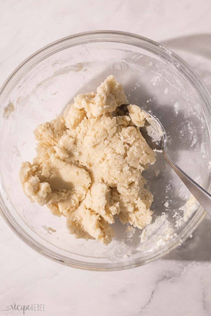 glass mixing bowl with dough and spoon in it.