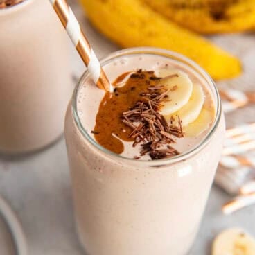 chocolate protein shake in a glass with a straw.