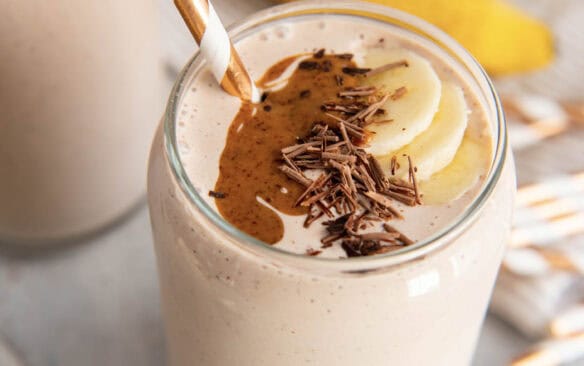 chocolate protein shake in a glass with a straw.