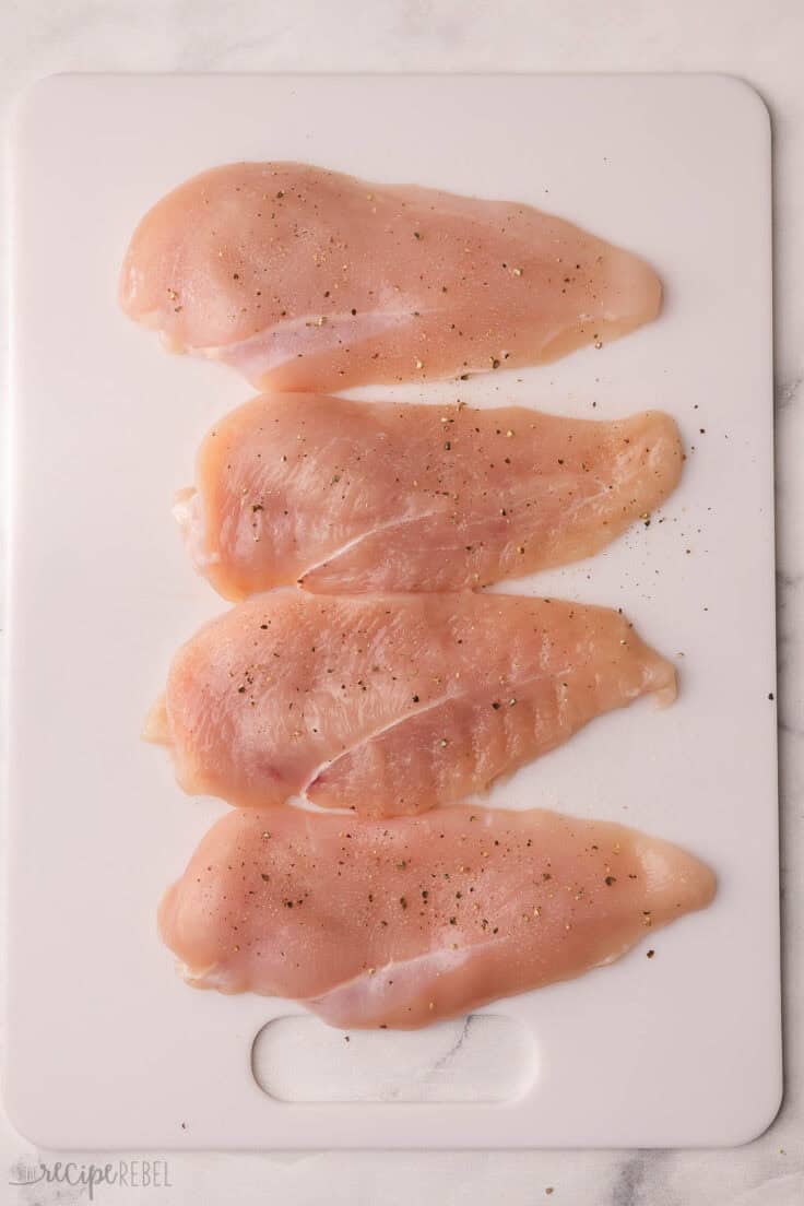 seasoned chicken breasts on white cutting board.