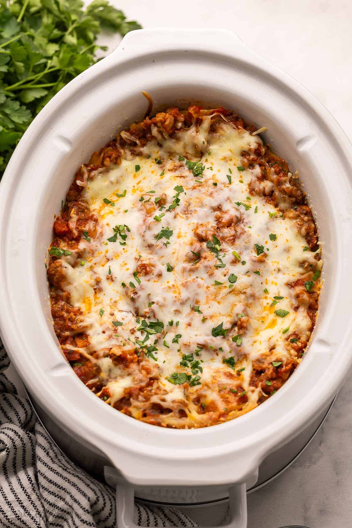 crockpot lasagna in crockpot topped with chopped parsley.