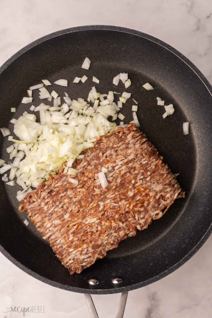 italian sausage and chopped onion in black pan.
