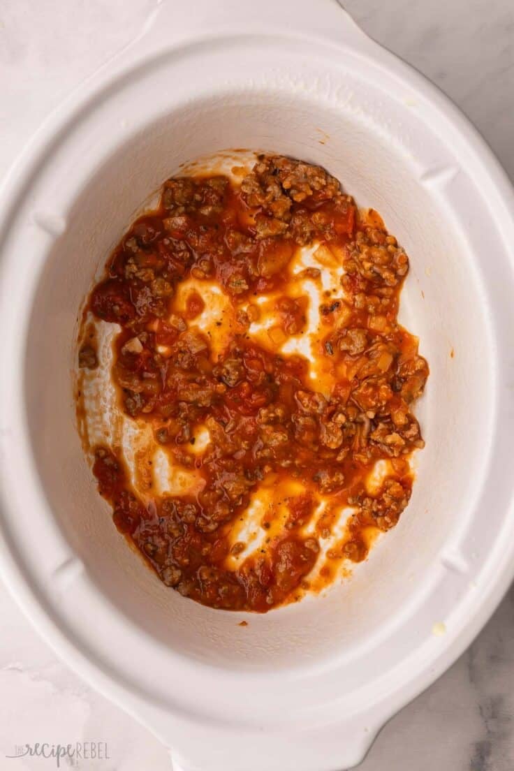 white crockpot with sauce spread on bottom.