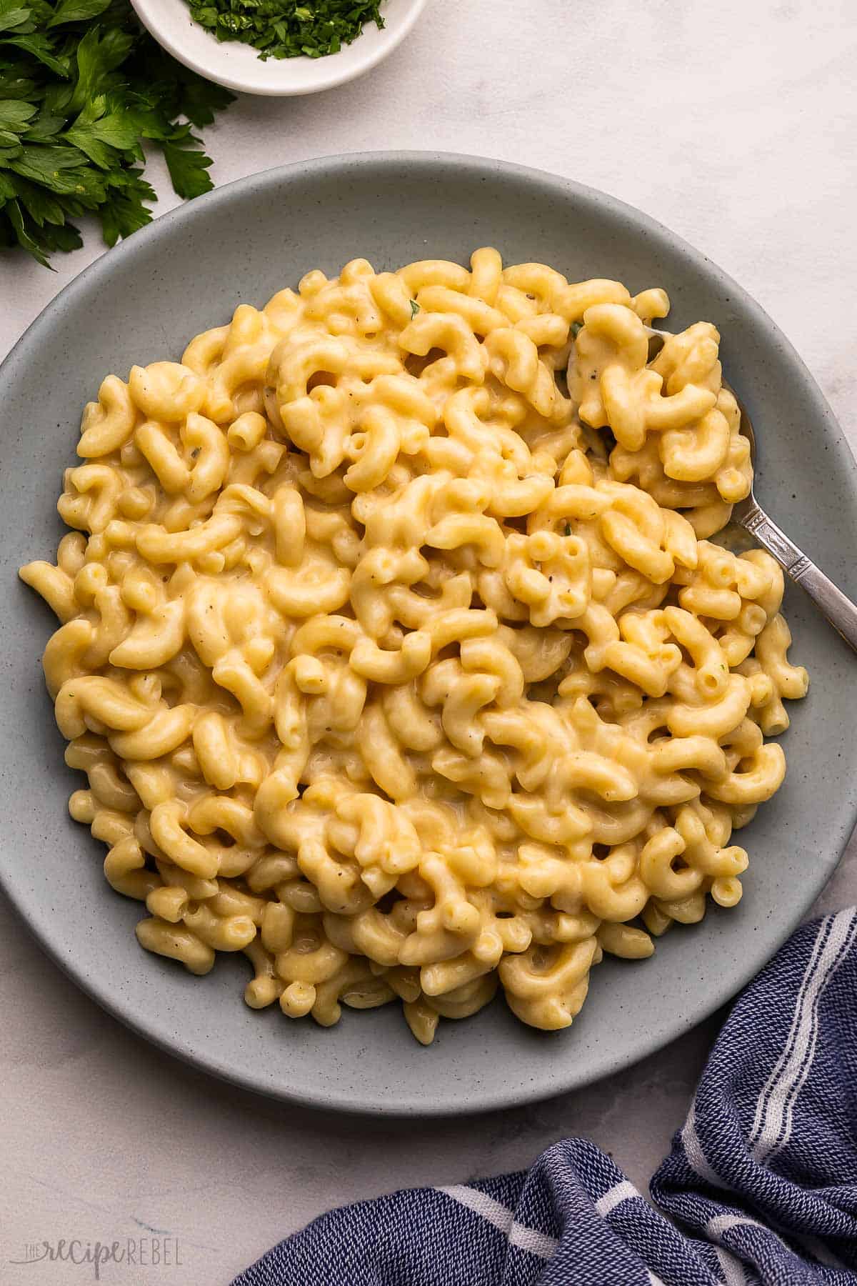 blue plate filled with mac and cheese and a fork.