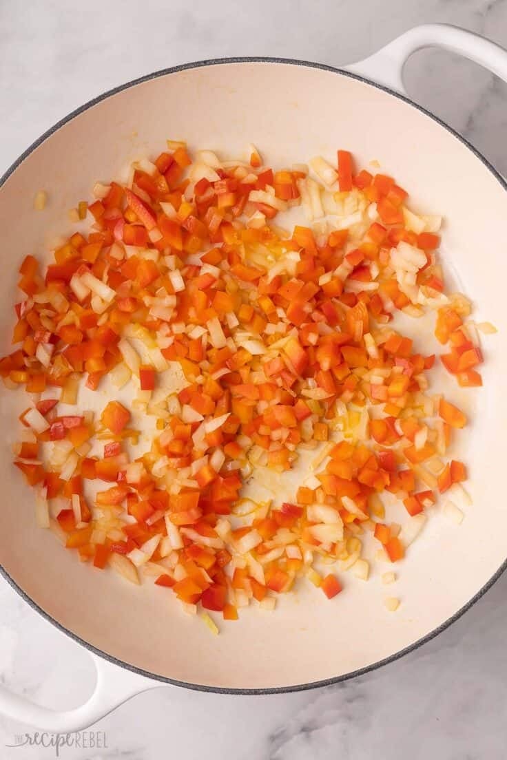 sauteed onion and peppers in a large white pan.