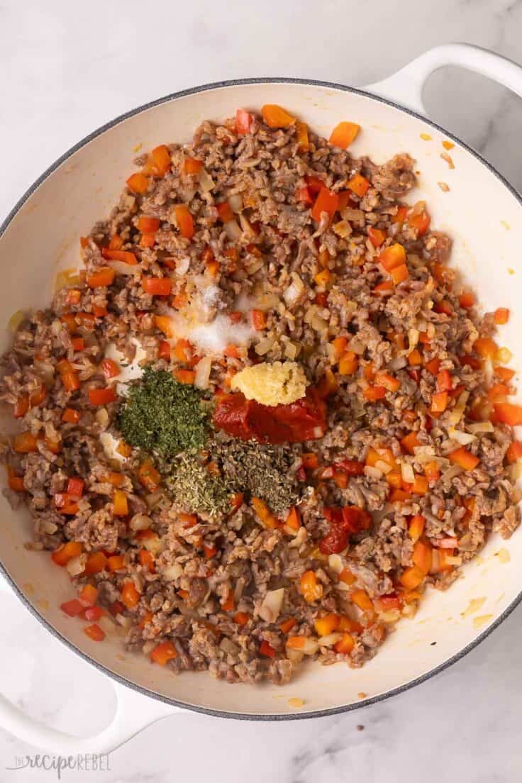 spices added to other ingredients in white skillet.