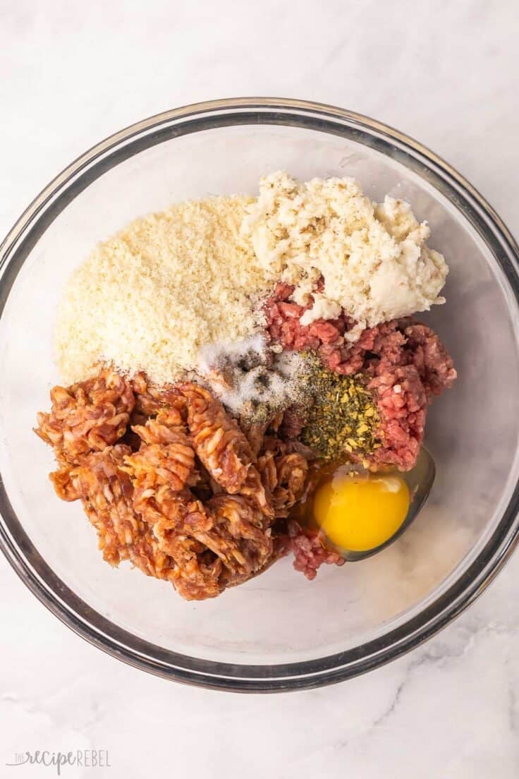glass mixing bowl with unmixed meatball ingredients.