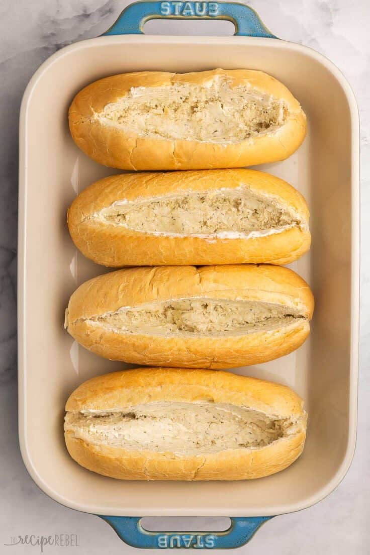 four buttered sub buns in pan.