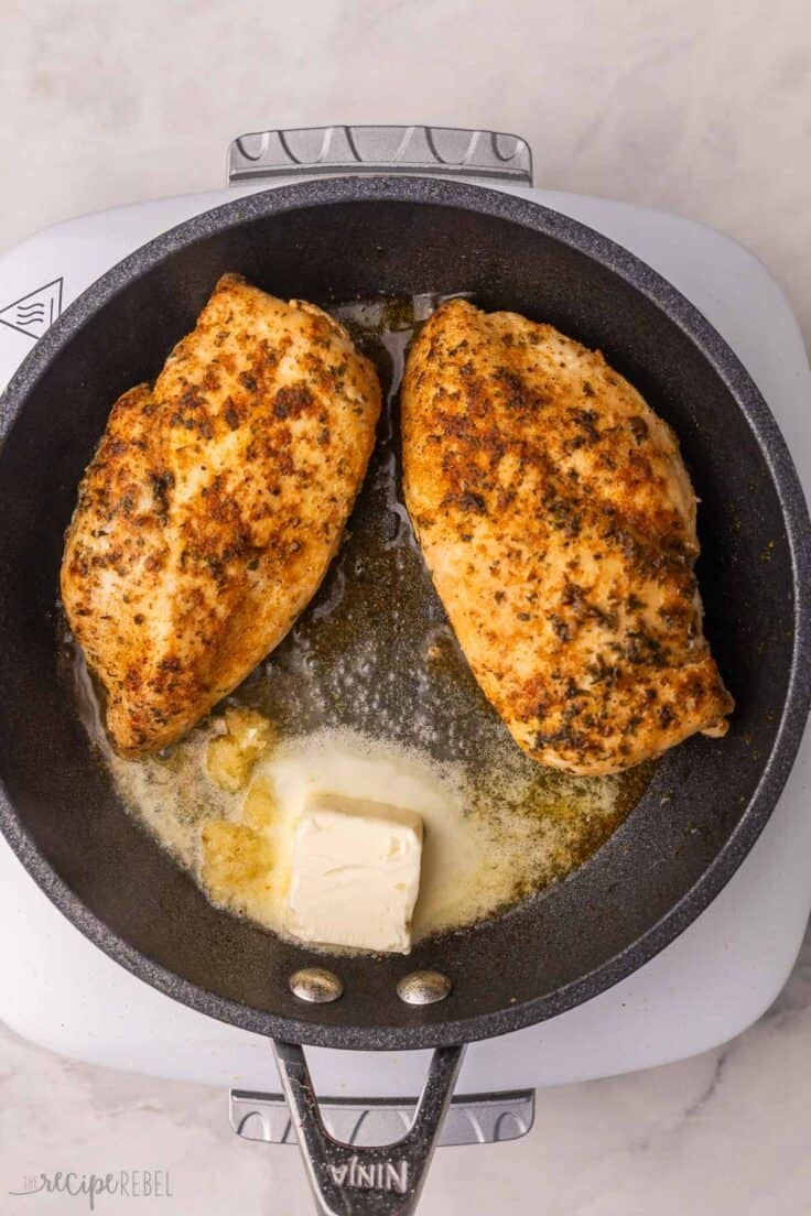 butter added to pan of cooking chicken breasts.
