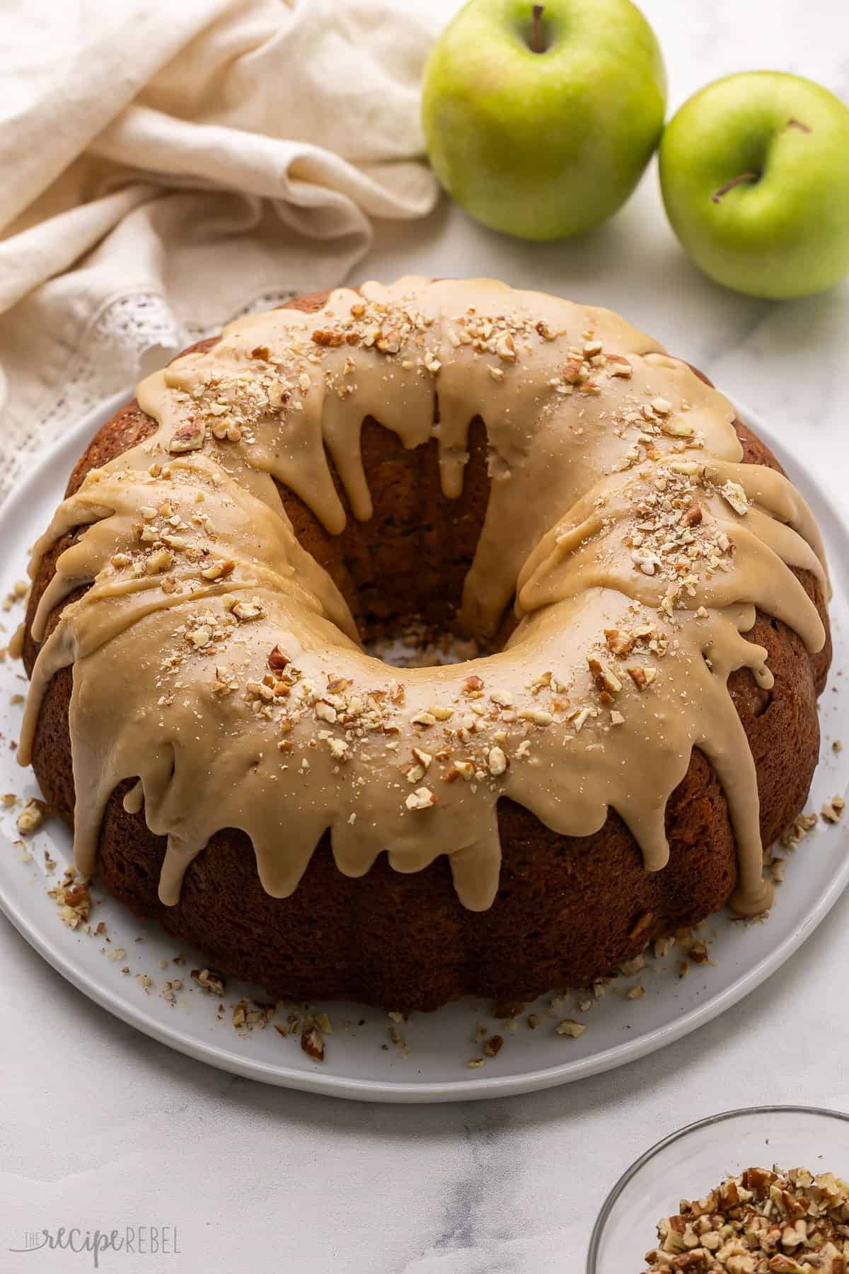a plate with apple bundt cake topped with glazed and chopped pecans.