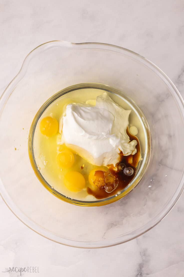 glass mixing bowl with unmixed eggs and other ingredients.