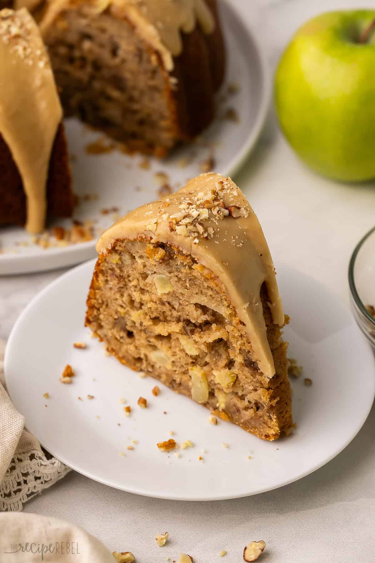 a slice of apple bundt cake with praline glaze and chopped pecans.