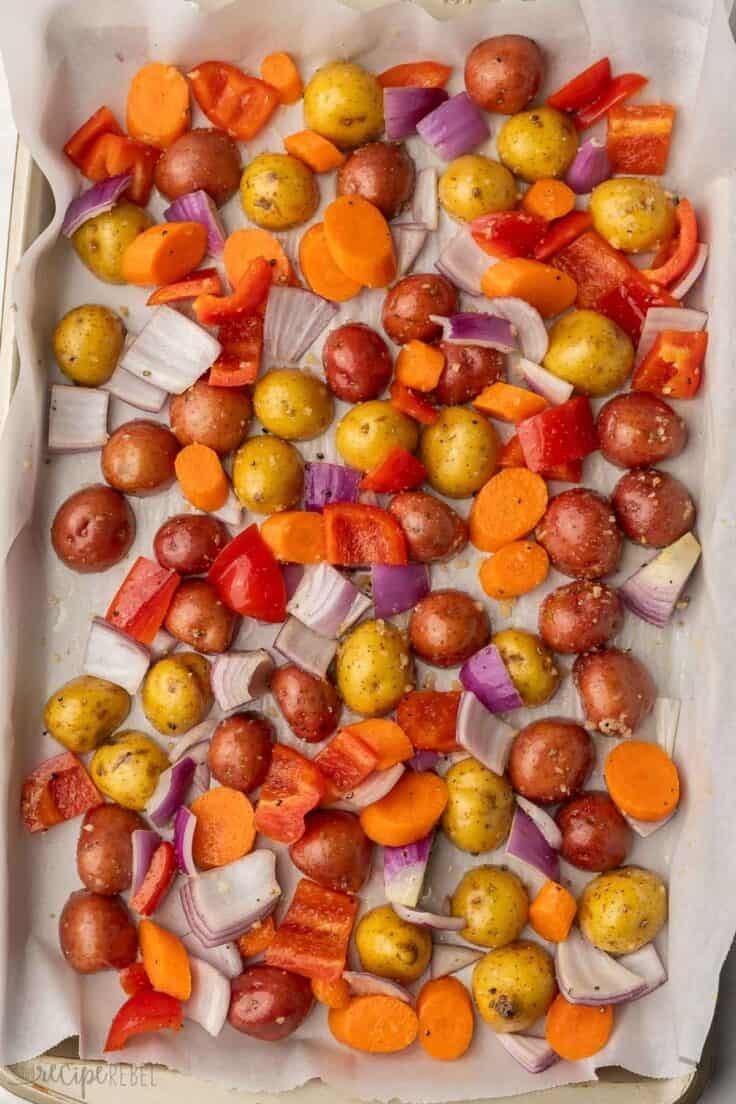 seasoned chopped vegetables on parchment lined baking sheet.